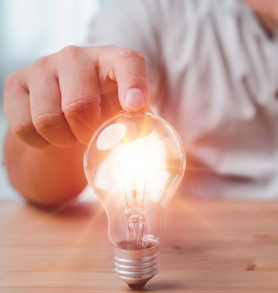 A person's finger touching an illuminated light bulb